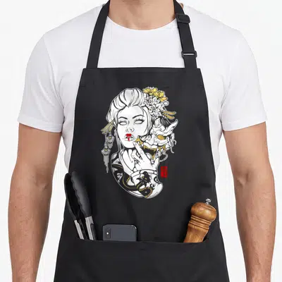 Succulent skull apron - Line art woman with yellow flowers and dragon tattoo holding a demon mask — shown on a black cotton canvas apron against a white background