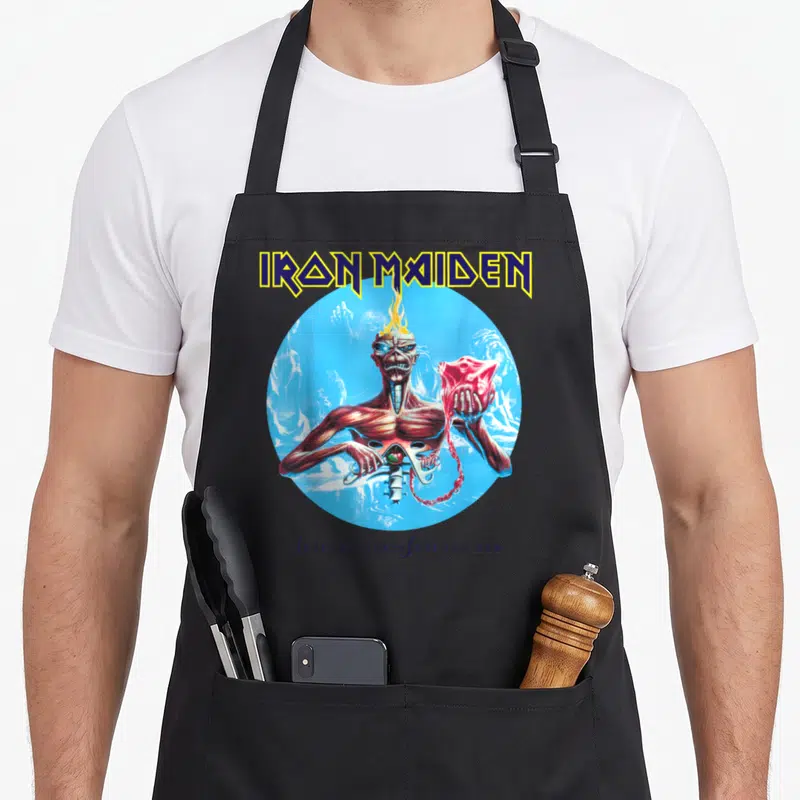 7th collection apron - Zombie creature holding red heart inside blue circle with IRON MAIDEN text above and Seventh Son — shown on a black cotton canvas apron against a white background
