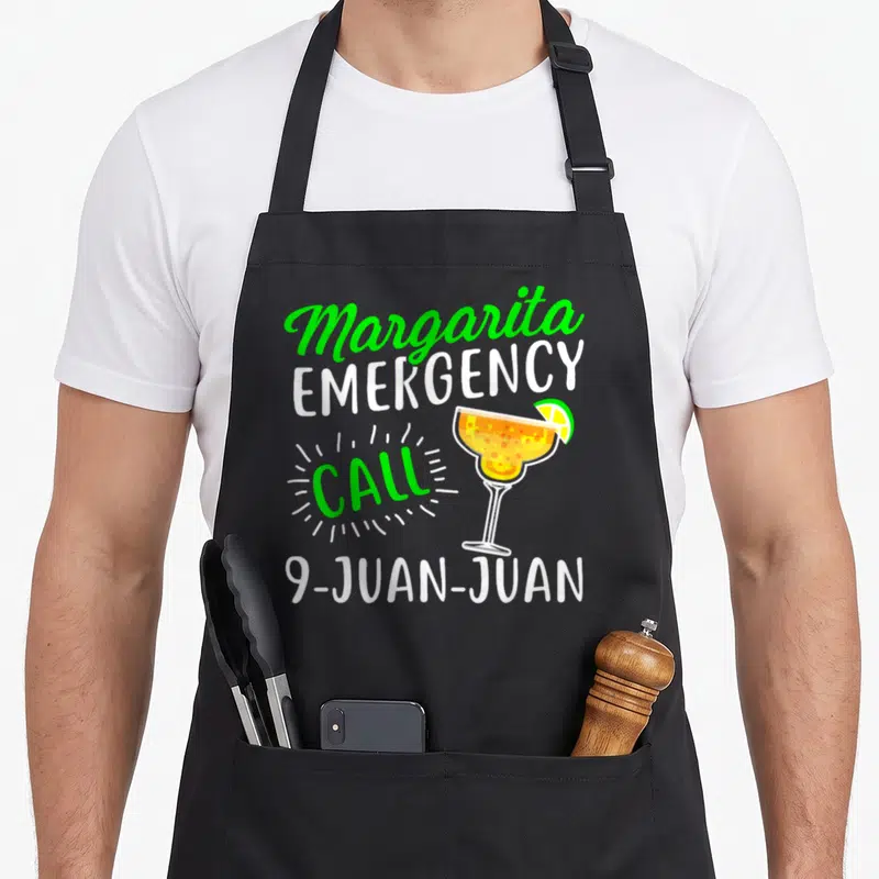 Margarita michelada apron - Margarita Emergency Call 9-Juan-Juan text with cartoon margarita glass and lime wedge — shown on a black cotton canvas apron against a white background
