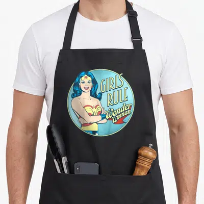 Rule single apron - Retro Wonder Woman portrait with stacked Girls Rule Wonder Woman text in a blue circle — shown on a black cotton canvas apron against a white background