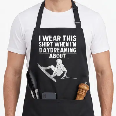 Wakeboarding christmas apron - Distressed white skier silhouette below stacked text reading I wear this shirt when I'm — shown on a black cotton canvas apron against a white background