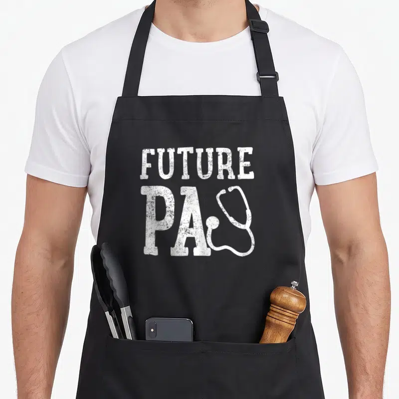 Vintage future doctor apron - White distressed FUTURE PA text with overlapping stethoscope graphic — shown on a black cotton canvas apron against a white background
