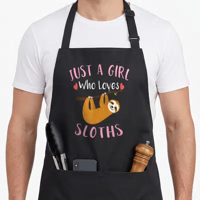 Vintage sloth apron - Text reading Just a Girl Who Loves Sloths above a hanging sloth illustration — shown on a black cotton canvas apron against a white background