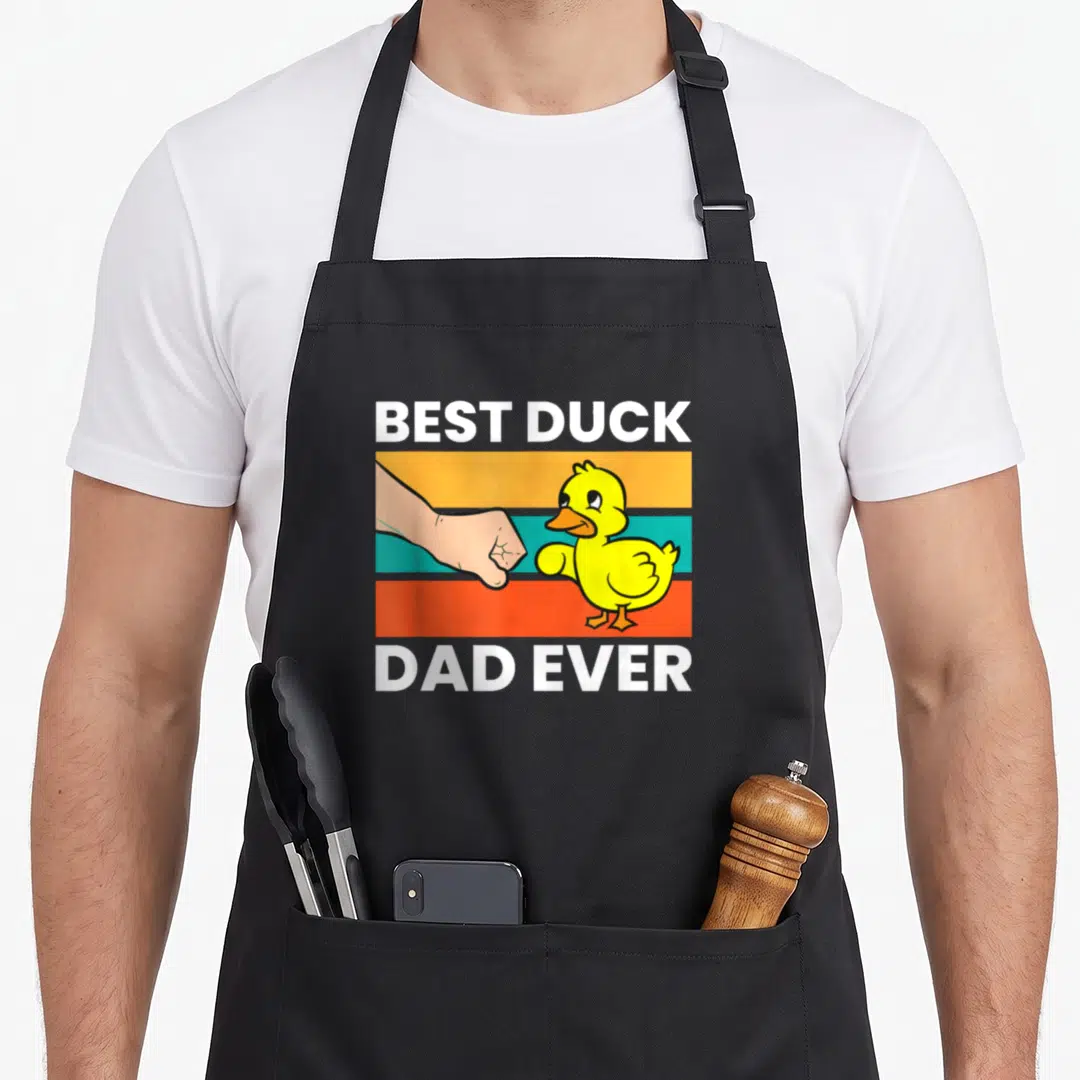 Papa cotton duck apron - Cartoon yellow duck fist-bumping human hand on orange teal red stripes with white text — shown on a black cotton canvas apron against a white background