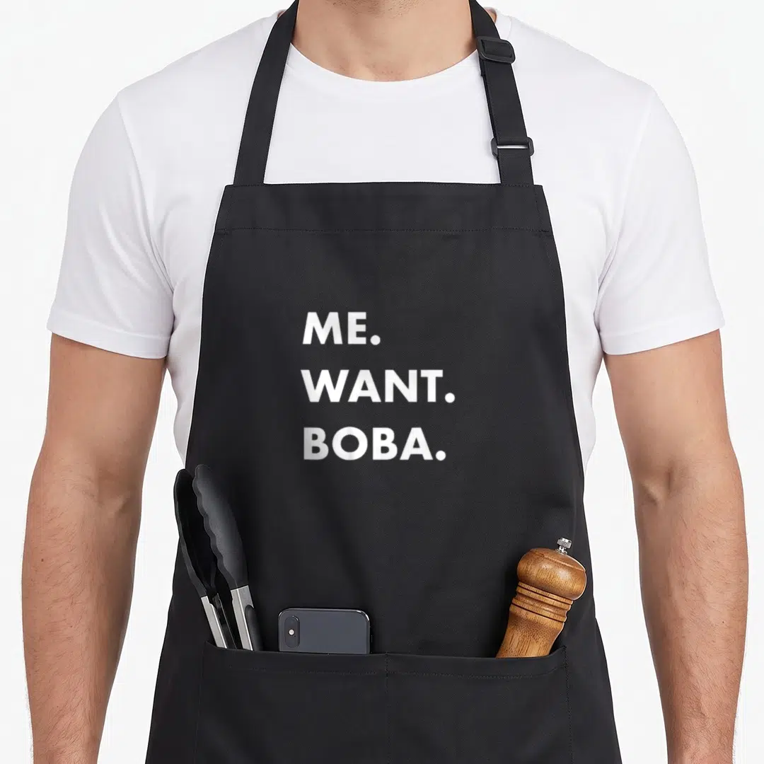 Boba asian apron - White stacked text reading ME. WANT. BOBA. on dark background — shown on a black cotton canvas apron against a white background