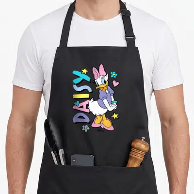 Icon daisy apron - Cartoon Daisy Duck beside vertical DAISY text with stars, flowers, hearts in pastel colors — shown on a black cotton canvas apron against a white background
