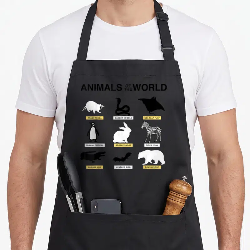 Animal meme apron - Minimalist animal silhouettes with labels Trash Panda, Danger Noodle, and Death Floof in black — shown on a black cotton canvas apron against a white background