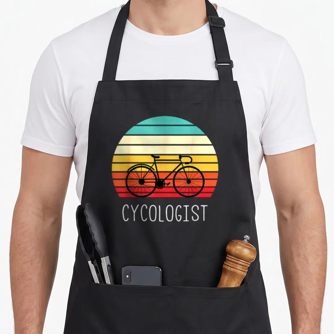 Cycologist cycling apron - Black bicycle over teal yellow orange red white striped sun with white text CYCOLOGIST — shown on a black cotton canvas apron against a white background