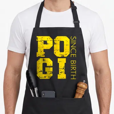 Pogi filipino apron - Yellow distressed POGI SINCE BIRTH vertical typography design — shown on a black cotton canvas apron against a white background