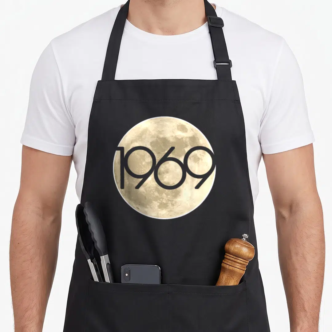 50th apollo apron - Beige moon photo with grey 1969 text overlay — shown on a black cotton canvas apron against a white background