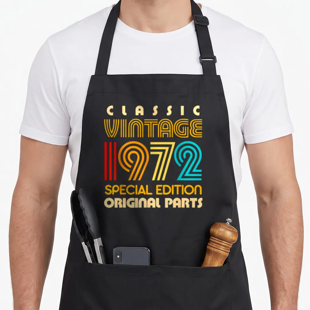 Special parts of an apron - Stacked text reading Classic Vintage 1972 Special Edition Original Parts in retro yellow — shown on a black cotton canvas apron against a white background
