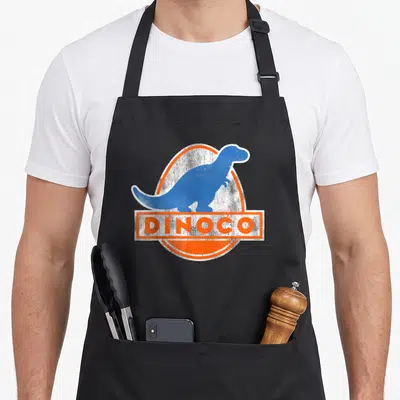 Iconic car apron - Blue dinosaur silhouette in orange oval with white DINOCO text box — shown on a black cotton canvas apron against a white background