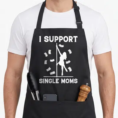 Strip offensive aprons - White I SUPPORT SINGLE MOMS text with pole dancer silhouette and floating dollar bills — shown on a black cotton canvas apron against a white background