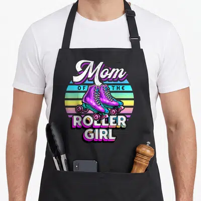 Roller skating family aprons - Mom of the Roller Girl text with purple skates on striped sunset background — shown on a black cotton canvas apron against a white background