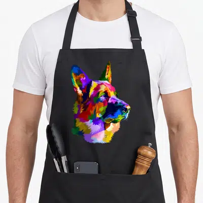 Pop dog mom apron - Colorful German Shepherd head in pop art style using blue, red, yellow, green, and purple — shown on a black cotton canvas apron against a white background