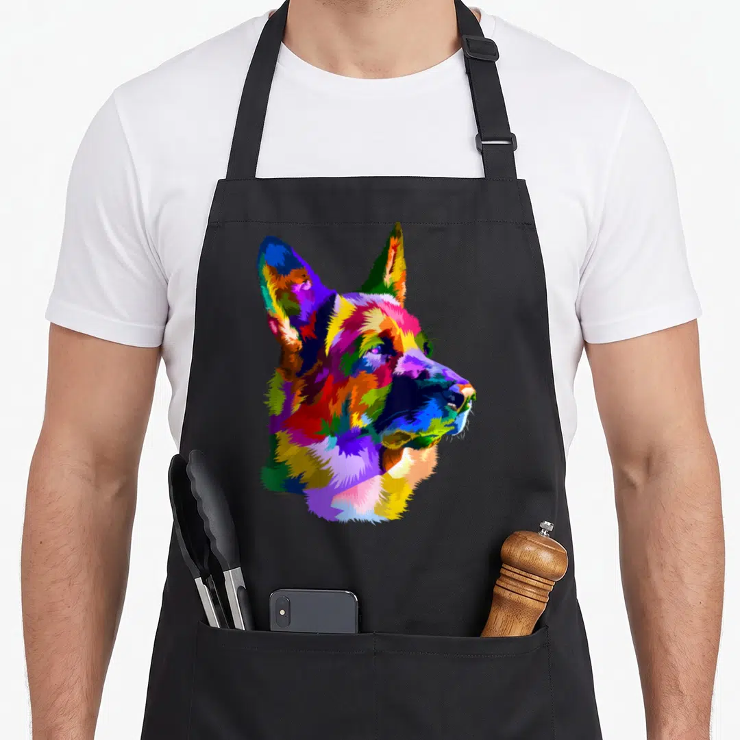 Pop dog mom apron - Colorful German Shepherd head in pop art style using blue, red, yellow, green, and purple — shown on a black cotton canvas apron against a white background