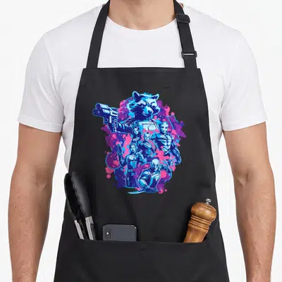 Volume galaxies apron - Rocket Raccoon holding gun above team figures against blue pink and purple splatter background — shown on a black cotton canvas apron against a white background