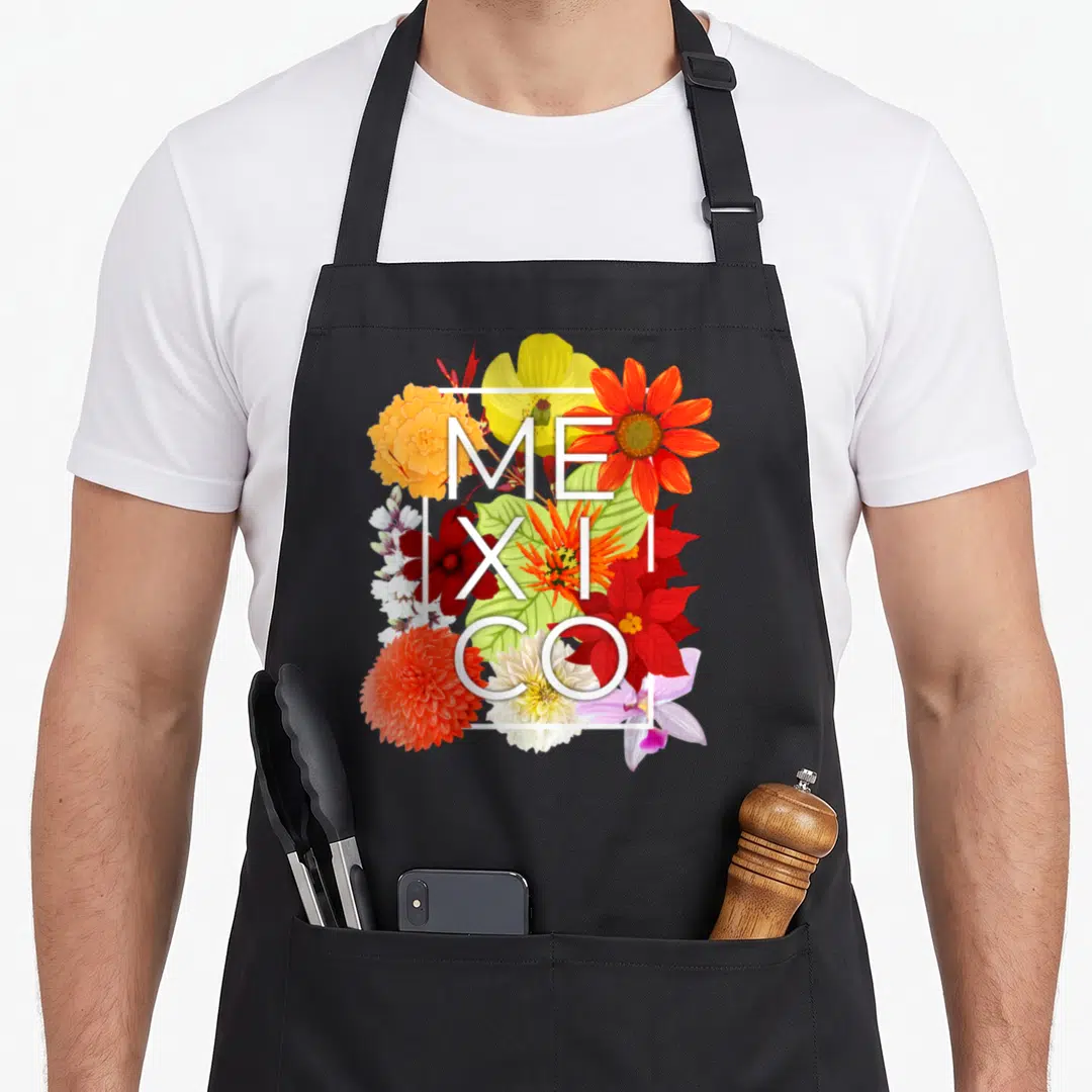 Flower mexico apron - White MEXICO text over red yellow orange and white flowers in a square frame — shown on a black cotton canvas apron against a white background