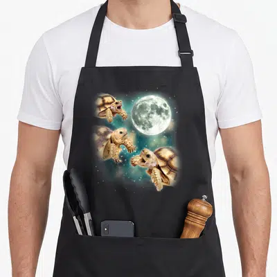 Tortoise meme apron - Three turtles howling at a moon in a teal starry space background — shown on a black cotton canvas apron against a white background