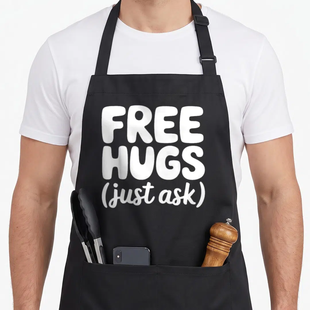 Hug unity day apron - White stacked text reading free hugs just ask on dark background — shown on a black cotton canvas apron against a white background