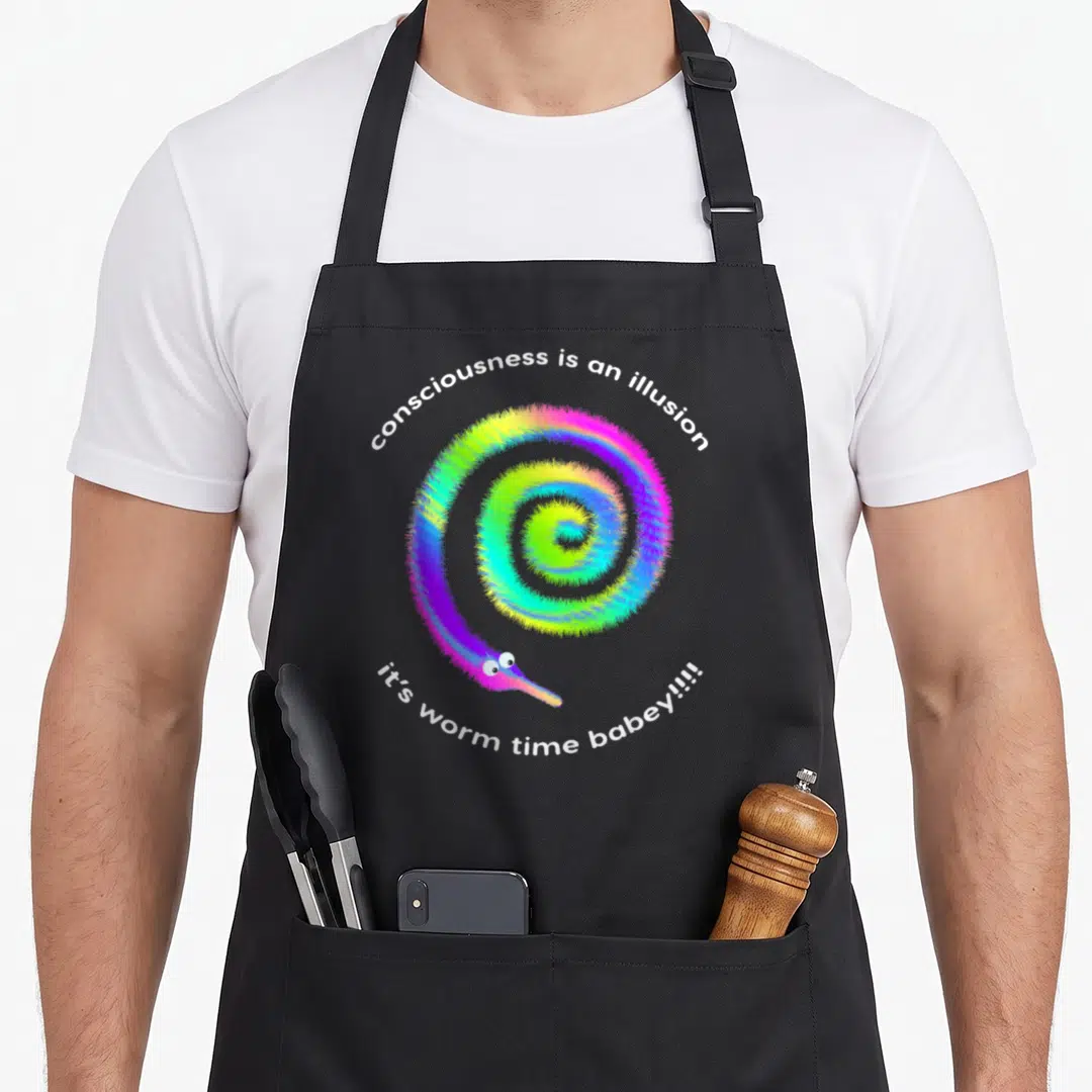 Consciousness meme apron - Rainbow fuzzy worm in spiral with white text consciousness is an illusion it's worm time — shown on a black cotton canvas apron against a white background
