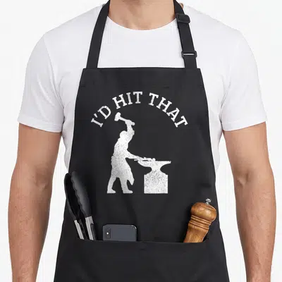 Schmied blacksmith apron - Arched I'D HIT THAT text above white blacksmith silhouette holding hammer over anvil — shown on a black cotton canvas apron against a white background