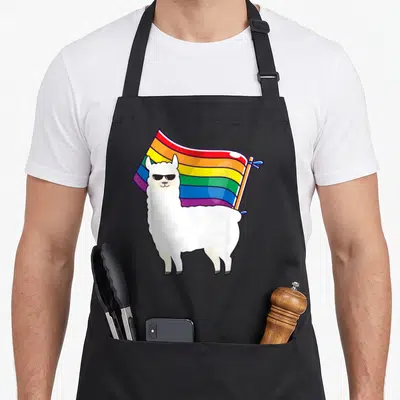 Lgbt gay apron - Cartoon white llama wearing sunglasses in front of a waving rainbow flag — shown on a black cotton canvas apron against a white background