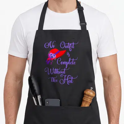 Hat chef outfit apron - Red hat with purple flowers and text No Outfit is Complete Without the Hat — shown on a black cotton canvas apron against a white background