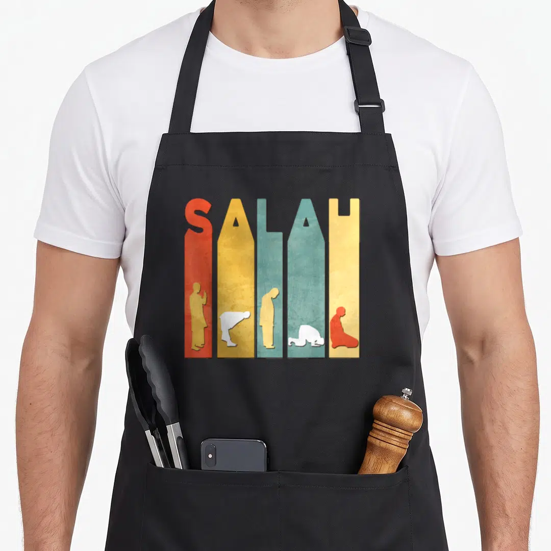 Kareem ramadan apron - SALAH text formed by colored vertical bars containing prayer posture silhouettes — shown on a black cotton canvas apron against a white background