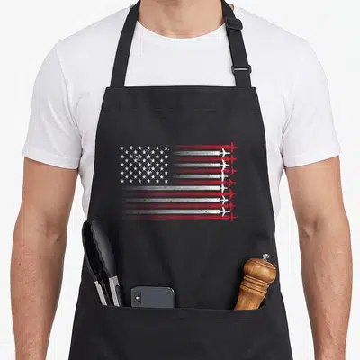 4th airplane apron - Stylized US flag with red white stripes forming airplane trails flying right in distressed print — shown on a black cotton canvas apron against a white background