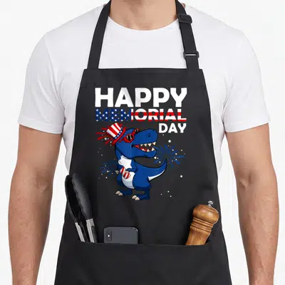 Hat 4th of july apron - Cartoon blue T-Rex in flag hat holding firework under stacked memorial day text — shown on a black cotton canvas apron against a white background