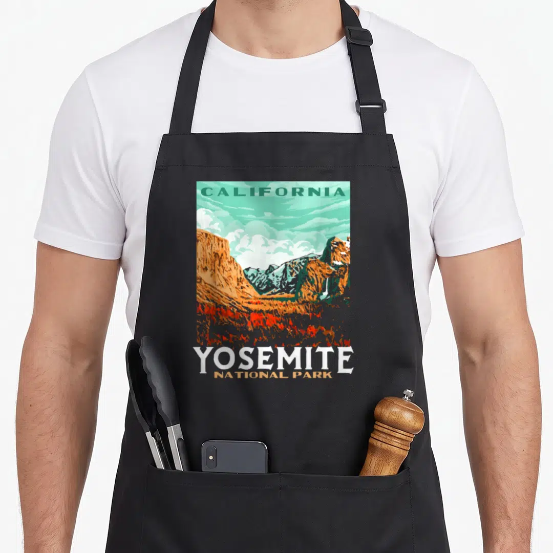 Yosemite national park apron - Retro California mountain landscape with waterfall and stacked YOSEMITE NATIONAL PARK — shown on a black cotton canvas apron against a white background