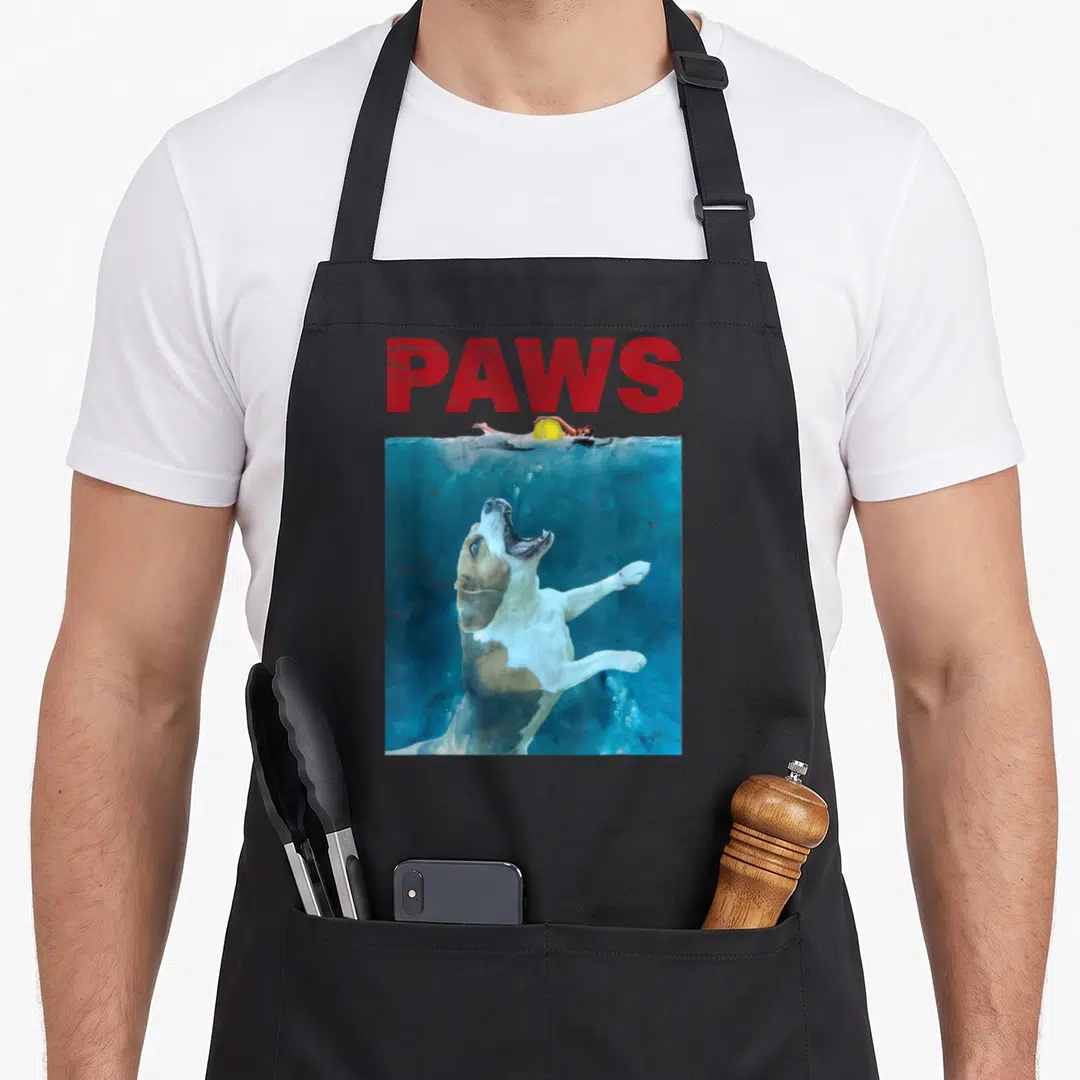 Underwater beagle apron - PAWS text above photo of brown and white dog leaping underwater — shown on a black cotton canvas apron against a white background