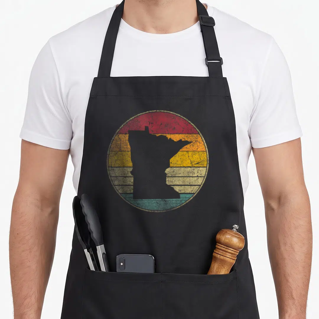 Distressed minnesota apron - Grey Minnesota map silhouette over red orange yellow beige teal horizontal stripes — shown on a black cotton canvas apron against a white background