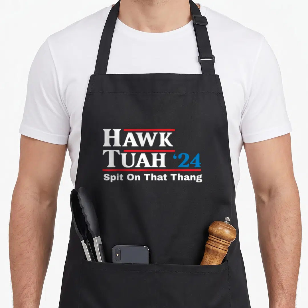 Tush hawk tuah apron - Stacked HAWK TUAH '24 text with red lines and Spit On That Thang slogan — shown on a black cotton canvas apron against a white background