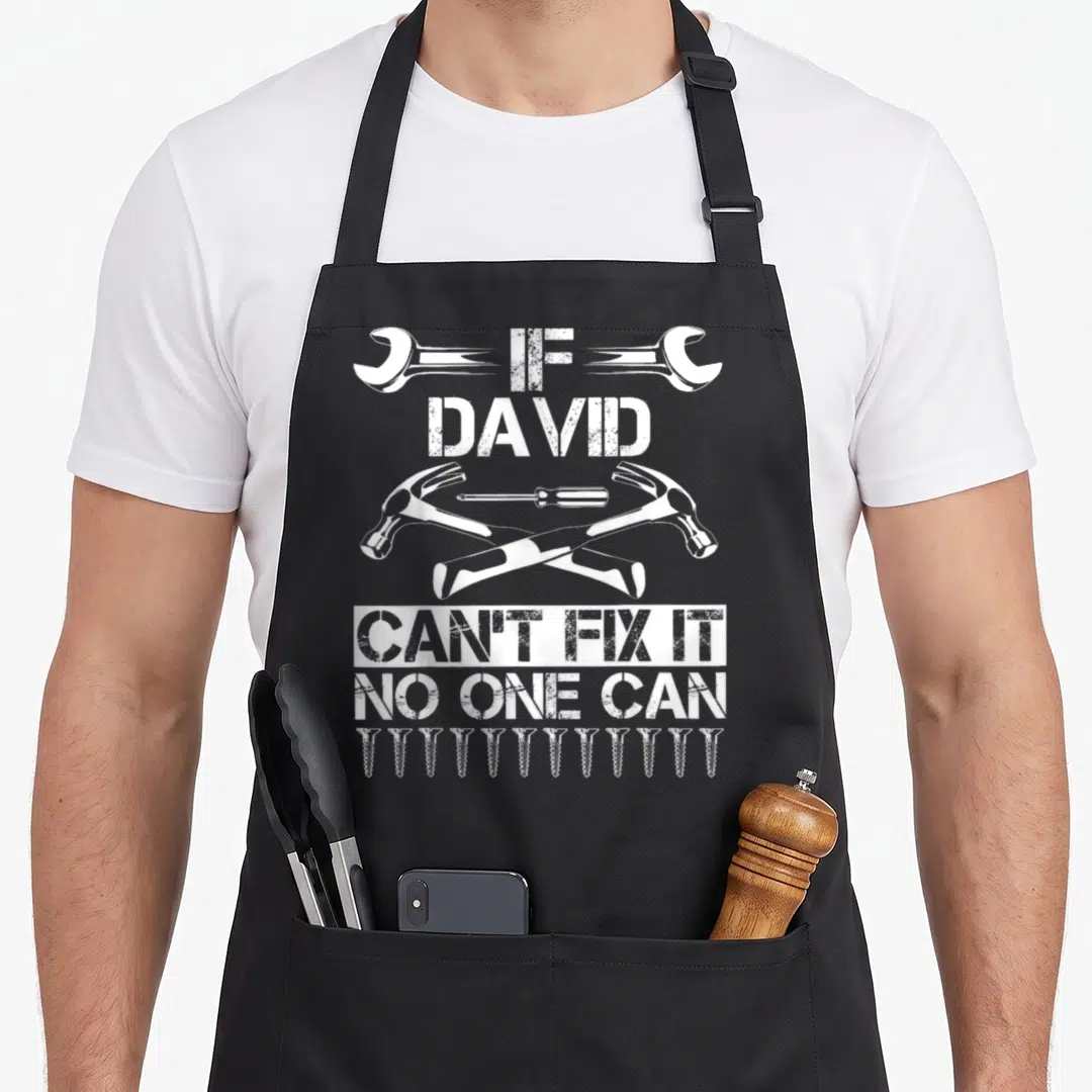 David father's day apron - White distressed text If David Can't Fix It No One Can with crossed hammers and screws — shown on a black cotton canvas apron against a white background