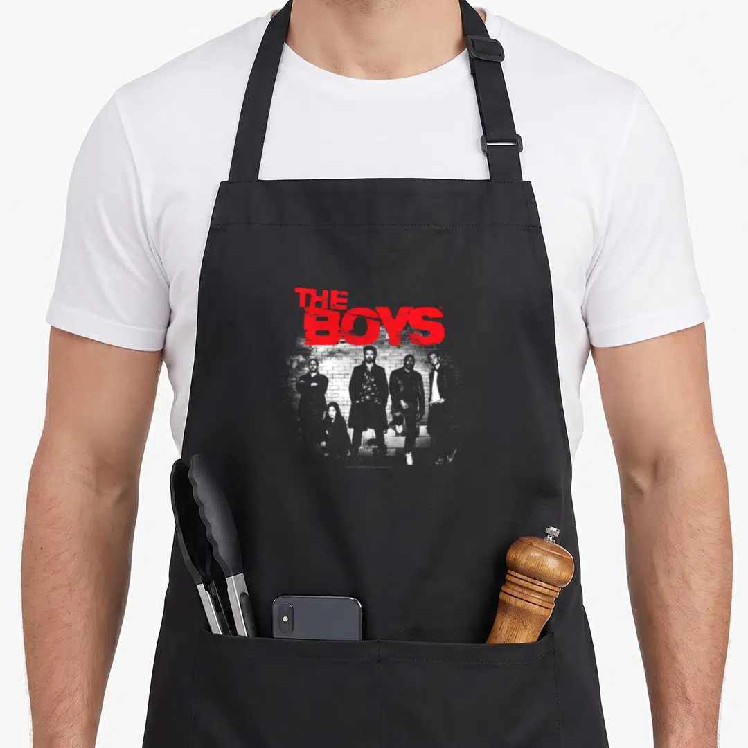 Graffiti show superhero apron - THE BOYS in distressed red text above five men standing against a brick wall in black — shown on a black cotton canvas apron against a white background