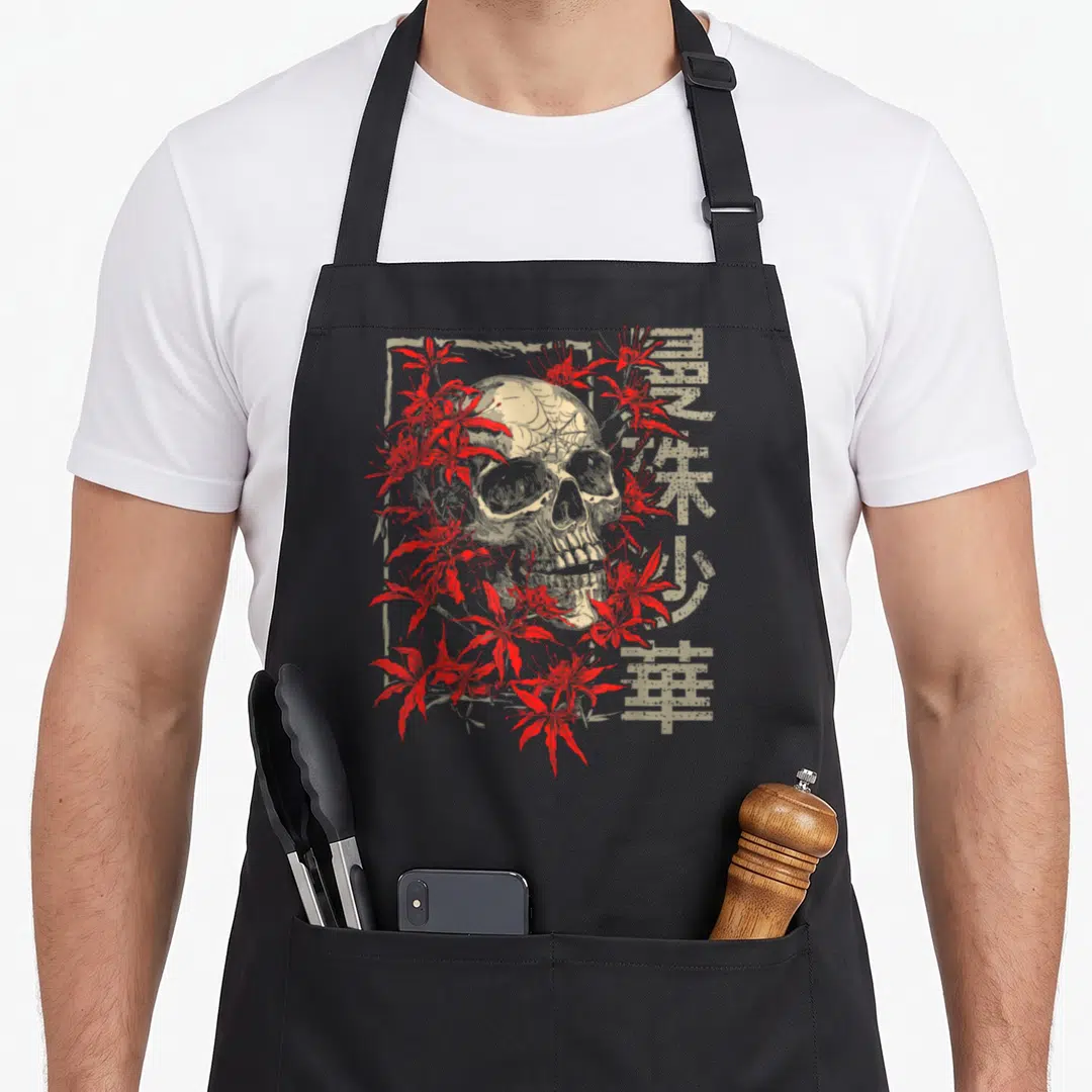 Spider white lily apron - Beige skull with red spider lilies and vertical kanji text in retro style — shown on a black cotton canvas apron against a white background