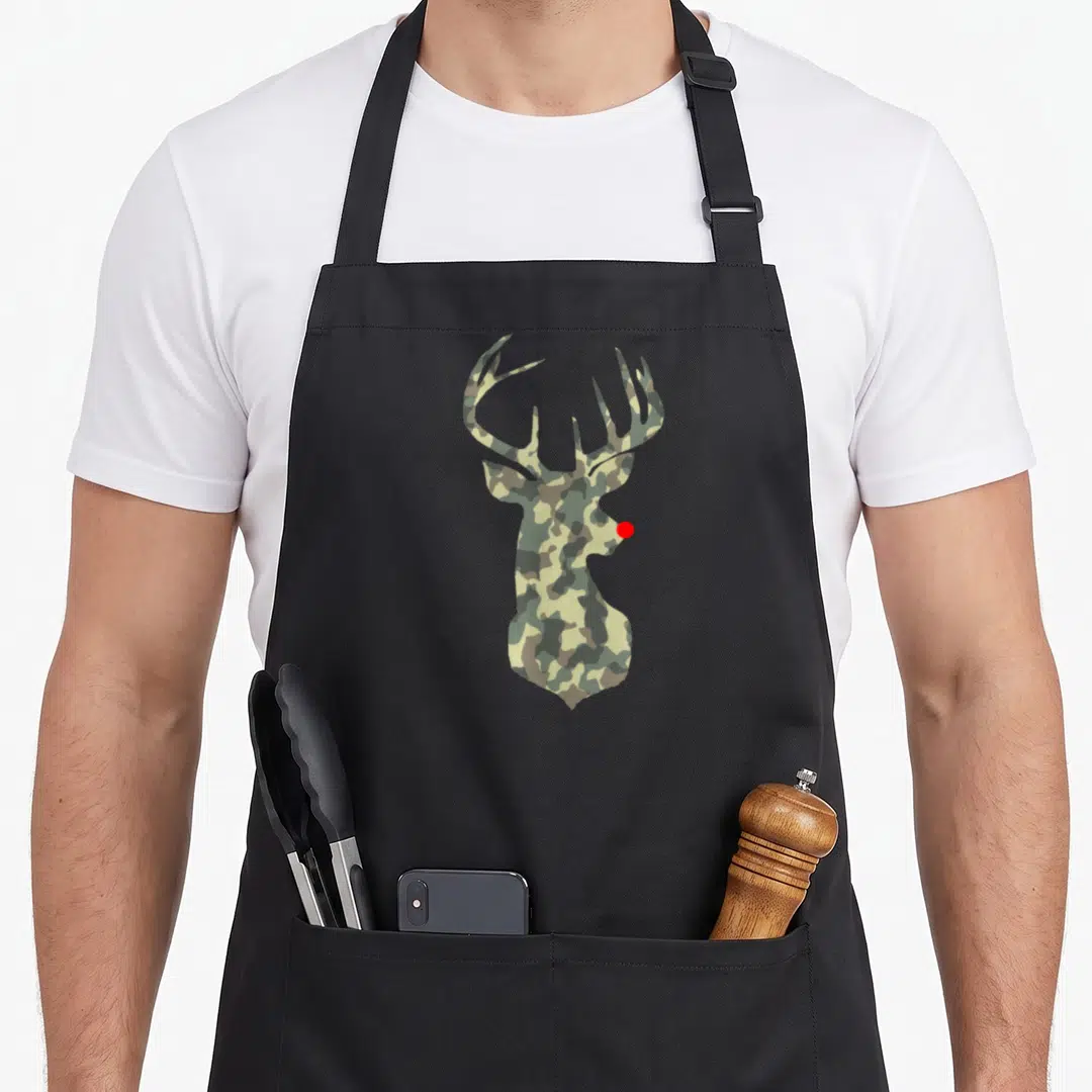 Rudolf reindeer apron - Deer head silhouette filled with green brown tan camouflage and single red dot nose — shown on a black cotton canvas apron against a white background