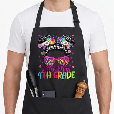 Miss messy aprons - Girl hairstyle with buns, heart sunglasses containing pencils, and Little Miss 4TH GRADE text — shown on a black cotton canvas apron against a white background