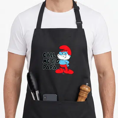 Funny call papa apron - Cartoon Smurf with red hat and pants stands beside stacked text CALL ME BIG PAPA — shown on a black cotton canvas apron against a white background