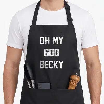 God distressed apron - White stacked typography reading OH MY GOD BECKY on black fabric — shown on a black cotton canvas apron against a white background