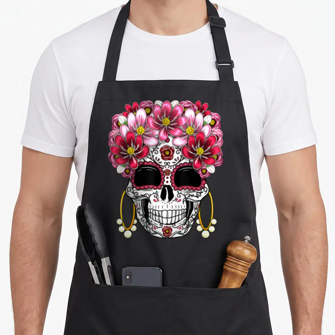 Muerto day of the dead apron - Decorated skull with pink red flowers and gold hoop earrings with pearls — shown on a black cotton canvas apron against a white background