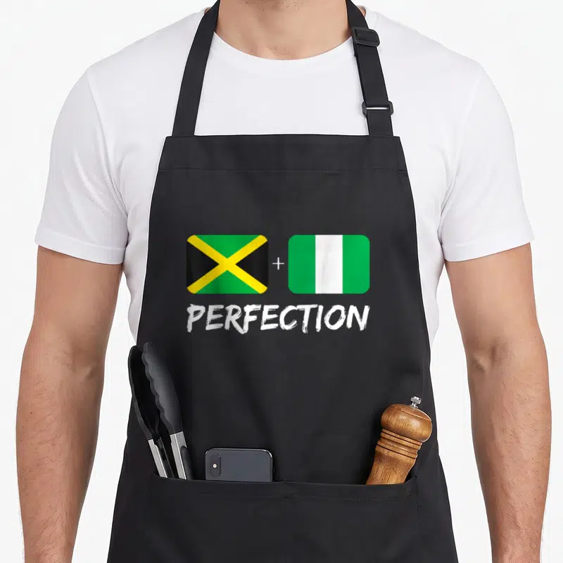 Nigerian heritage aprons - Two flags with plus sign and PERFECTION text in green yellow white black — shown on a black cotton canvas apron against a white background