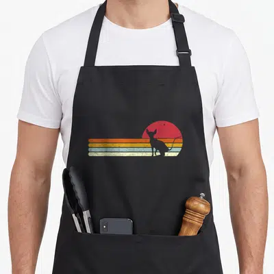 Silhouette cat apron - White cat silhouette sitting before red sun and four horizontal stripes in orange yellow blue — shown on a black cotton canvas apron against a white background