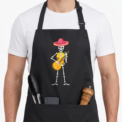 Hat mexican apron - Cartoon skeleton in pink sombrero and yellow vest playing guitar — shown on a black cotton canvas apron against a white background