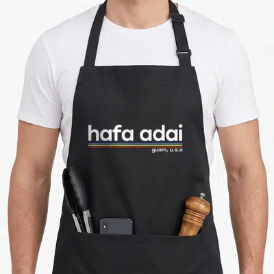 Adai guam aprons - hafa adai text with white blue yellow red lines and guam u.s.a label — shown on a black cotton canvas apron against a white background