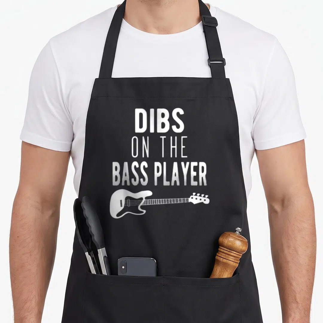 Dib bassist apron - White DIBS ON THE BASS PLAYER text stacked above a bass guitar silhouette — shown on a black cotton canvas apron against a white background