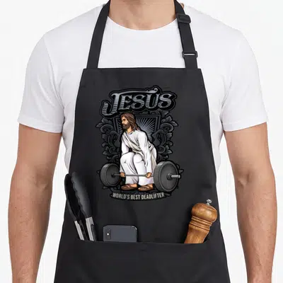 Alexis christian apron - Cartoon Jesus crouching with barbell under text JESUS WORLD'S BEST DEADLIFTER in white grey — shown on a black cotton canvas apron against a white background