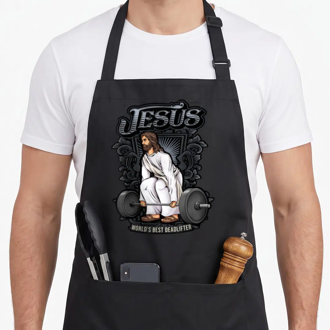 Alexis christian apron - Cartoon Jesus crouching with barbell under text JESUS WORLD'S BEST DEADLIFTER in white grey — shown on a black cotton canvas apron against a white background